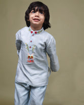 Baby blue bun bandhgala kurta pyjama set features intricate hand embroidery around the placket and collar with a delightful Bluey motif and shimmering mirror glare details. Fun, colorful buttons add a playful touch, while solid elastic pyjamas ensure comfort and a secure fit
