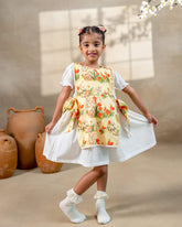 LAAD`S Girl in floral apron dress with a bunny and tulip print, layered over a white puff-sleeve dress. Features ruffled side panels and delicate lace trim. Soft, breathable fabric for comfort and charm.