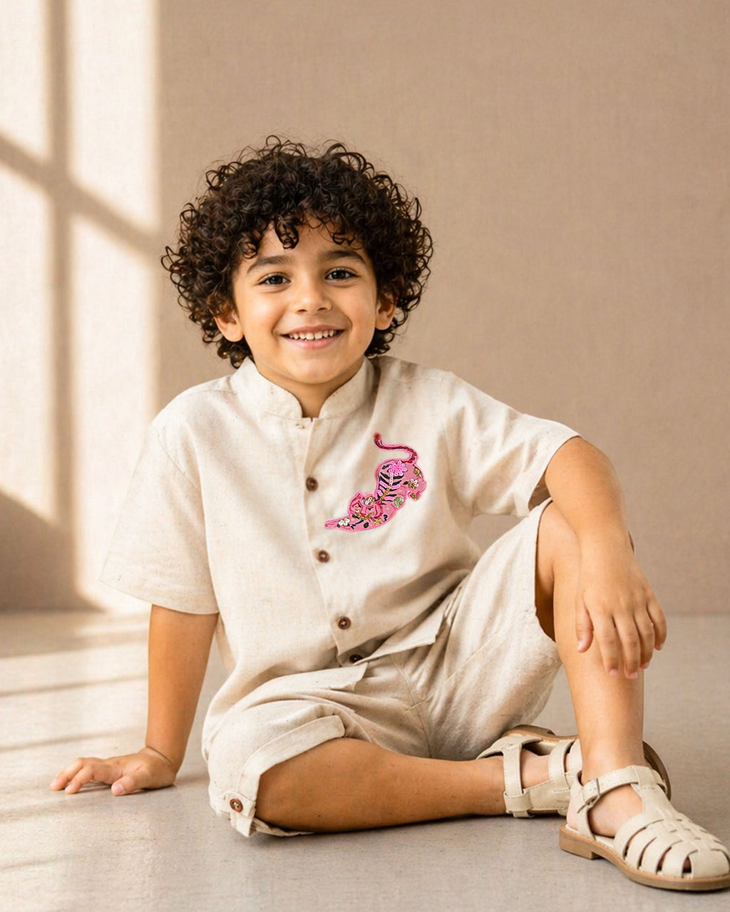Arlo Co-ord by LAADINDIA — boys beige cotton-linen co-ord set featuring a mandarin collar shirt with wooden button closure, handcrafted pink tiger appliqué embroidery, and matching tailored shorts