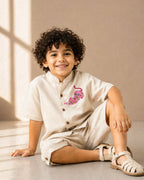 Arlo Co-ord by LAADINDIA — boys beige cotton-linen co-ord set featuring a mandarin collar shirt with wooden button closure, handcrafted pink tiger appliqué embroidery, and matching tailored shorts