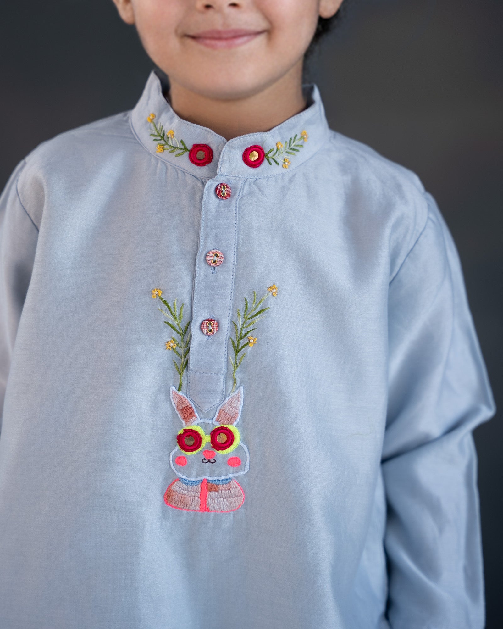 Baby blue bun bandhgala kurta pyjama set   features intricate hand embroidery around the placket and collar with a delightful Bluey motif and shimmering mirror glare details. Fun, colorful buttons add a playful touch, while solid elastic pyjamas ensure comfort and a secure fit
