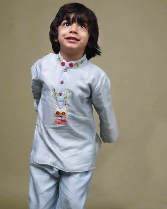 Baby blue bun bandhgala kurta pyjama set   features intricate hand embroidery around the placket and collar with a delightful Bluey motif and shimmering mirror glare details. Fun, colorful buttons add a playful touch, while solid elastic pyjamas ensure comfort and a secure fit