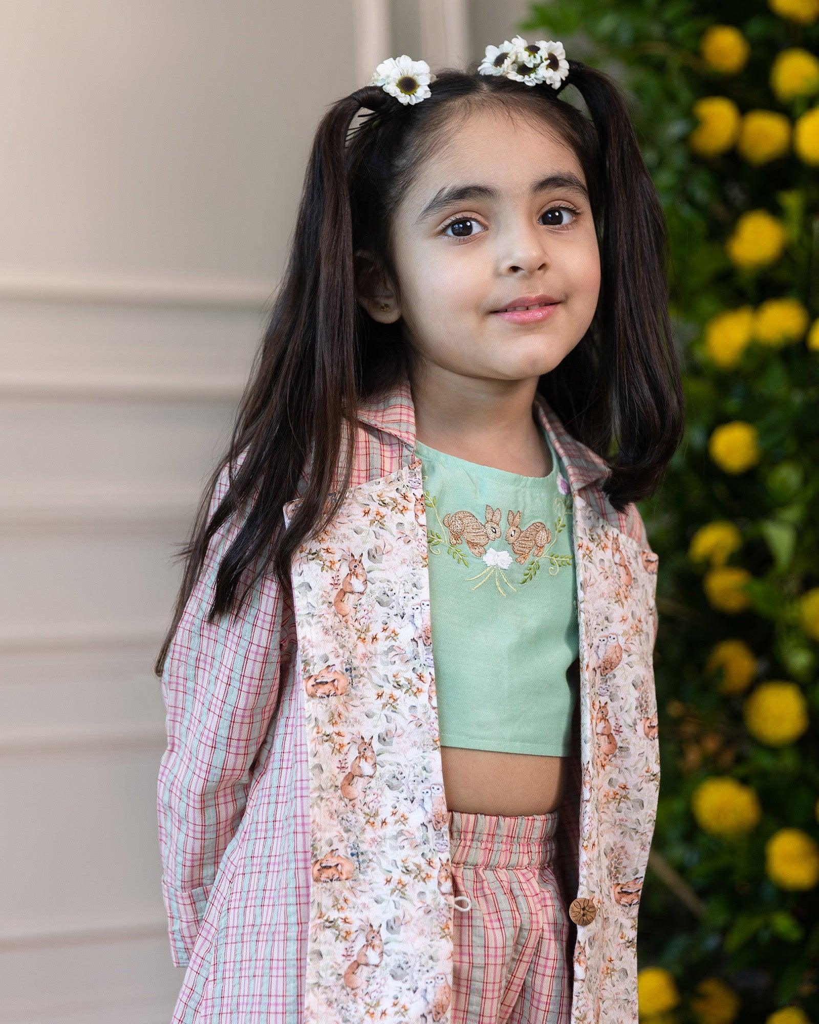 A vibrant Blooming Meadow Co-ord Set featuring a sleeveless silk Chanderi crop top with playful bunny embroidery and intricate threadwork, paired with a long coat featuring a meadow-inspired printed collar. Complete with breezy culottes pants that offer a stylish yet comfortable kidswear fit.