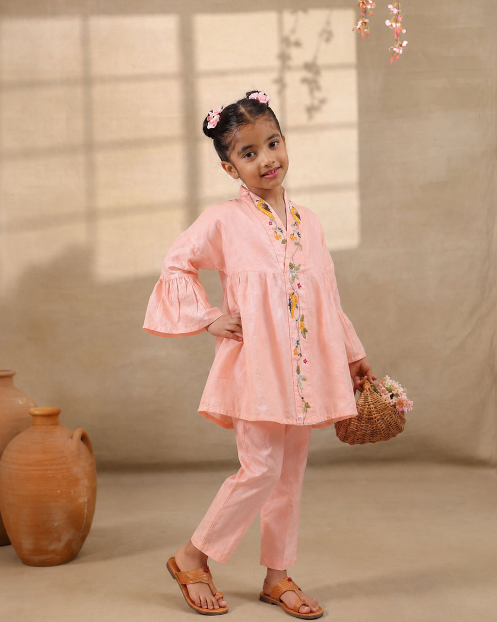 A young girl modeling a white kimono  flower look co-ord   set with colorful floral bird embroidery down the front placket by laandindia.com