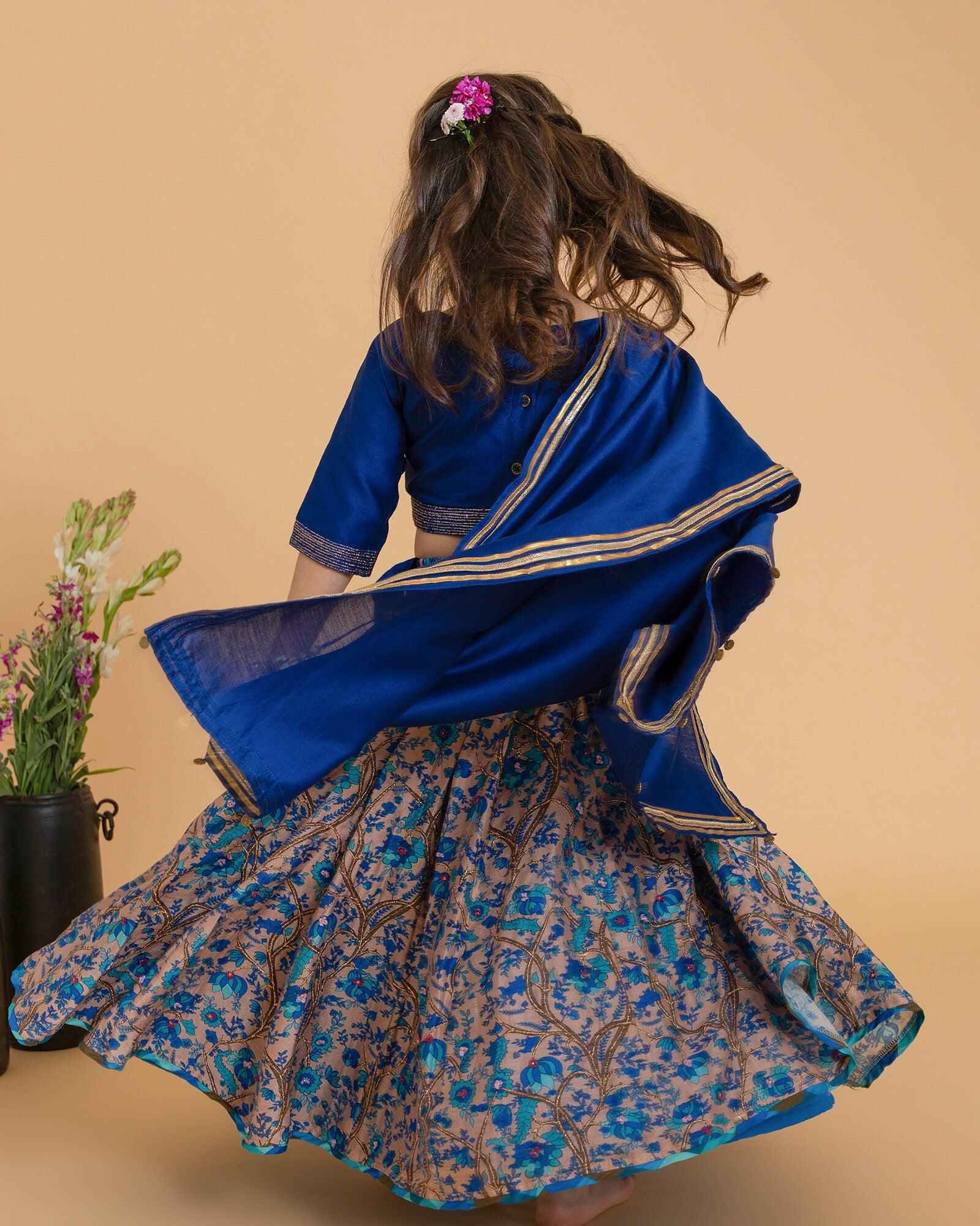 Girl in a midnite blue Midnite Phulwari lehenga embroidered blouse with intricate detailing, paired with a floral printed kids lehenga choli and dupatta with a gold border.
