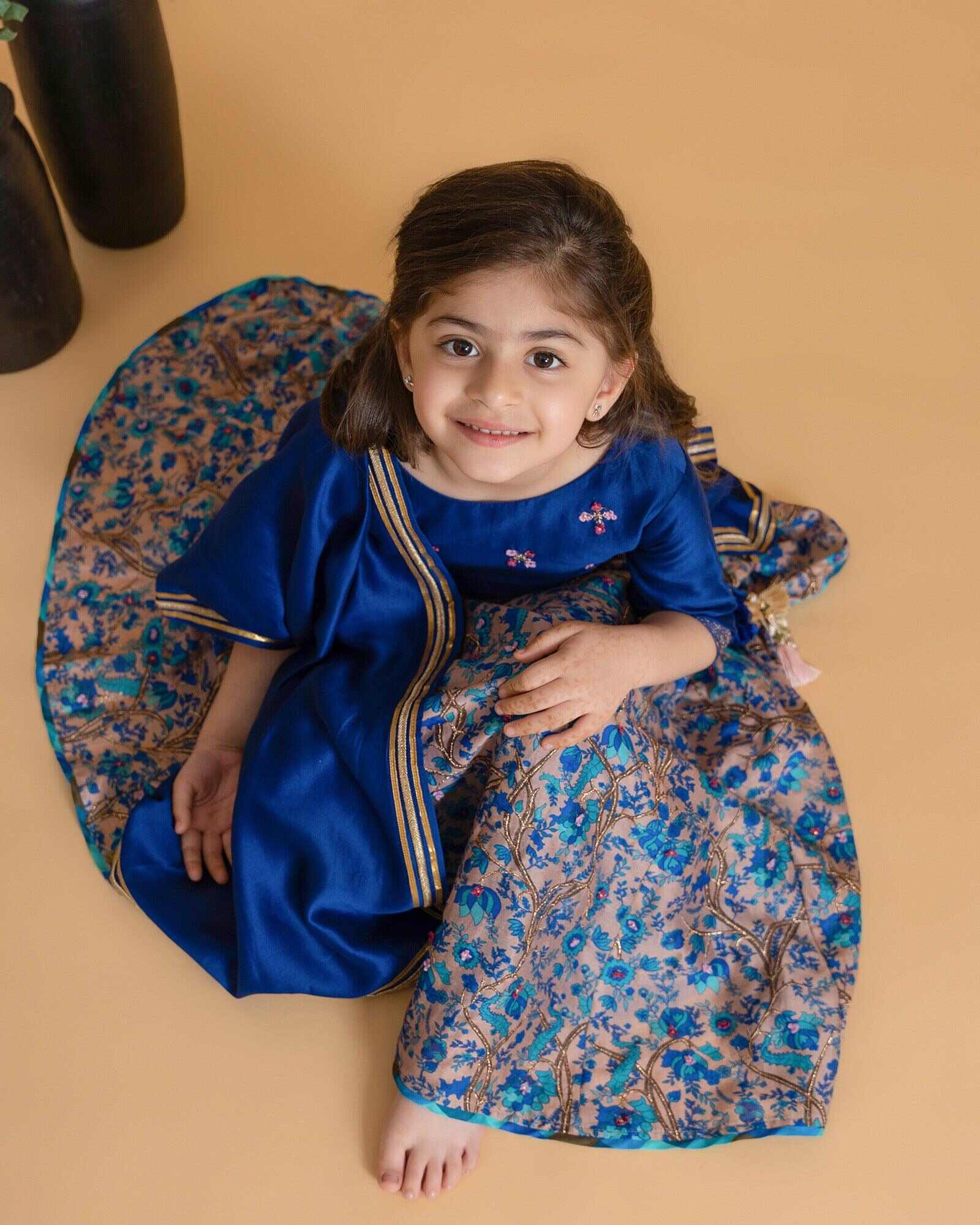 Girl in a midnite blue Midnite Phulwari lehenga embroidered blouse with intricate detailing, paired with a floral printed kids lehenga choli and dupatta with a gold border.