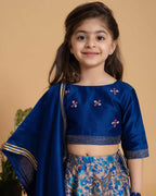 Girl in a midnite blue Midnite Phulwari lehenga embroidered blouse with intricate detailing, paired with a floral printed kids lehenga choli and dupatta with a gold border.