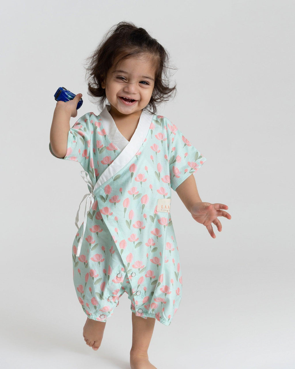 happy toddler Laad`s girl wearing a mint green kimono-style romper with pink tulip floral print .