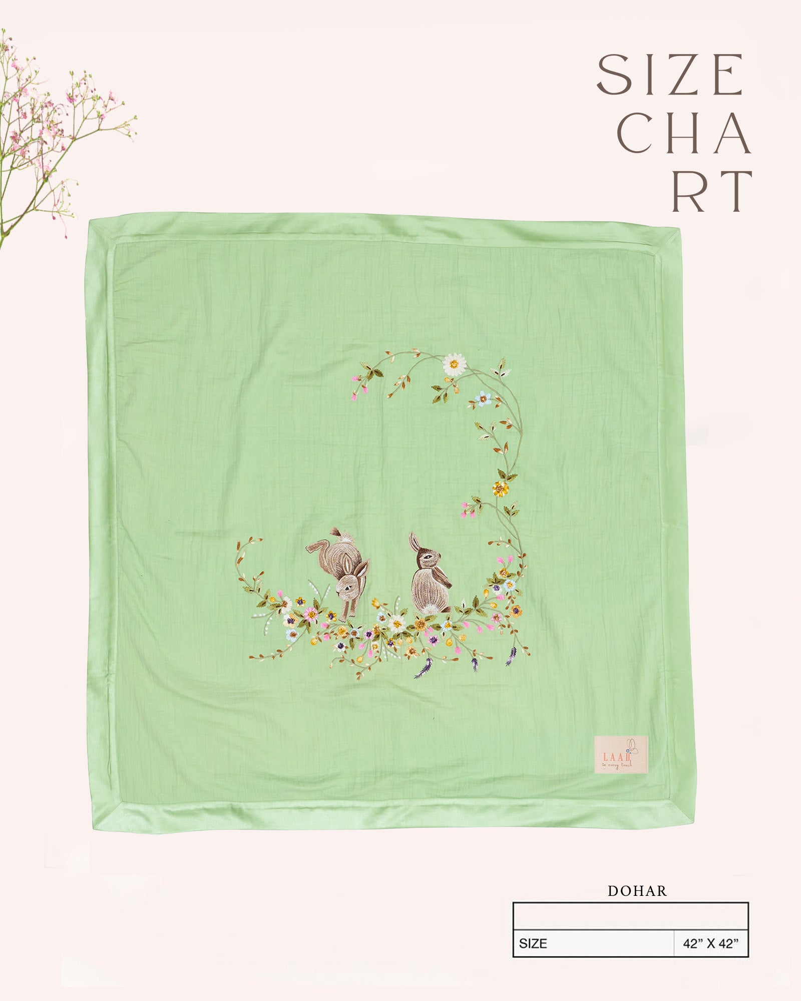 Soft green baby dohar with delicate embroidery featuring two bunnies surrounded by a floral wreath. Made from lightweight, breathable fabric with a satin border—perfect for cozy naps and gentle on baby’s skin.