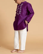 laad`s kid in japanese voilet kurta with embroideret  details on placket, paired  with off white trousers.