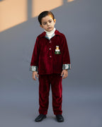 redvelvet co-ord set by LAADINDIA.com, featuring a child dressed in a red velvet co-ord with  embroidery, front-open top with contrast check cuffs, and matching trousers for winter occasion wear.