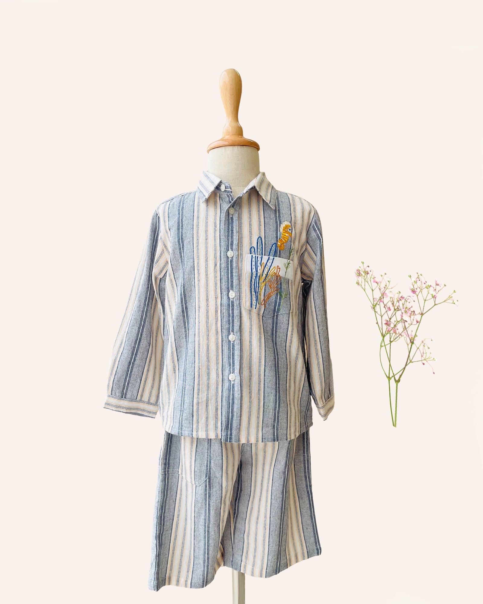 laad`s Kids' striped co-ord set with a long-sleeve shirt and shorts, featuring soft beige and gray tones. Embroidered seahorse detail adds a playful touch. Lightweight, breathable fabric for all-day comfort.
