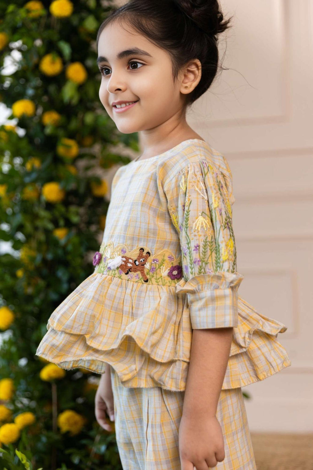 Adorable girls' yellow checkered co-ord set by Laad India, featuring intricate floral and animal embroidery, ruffled peplum top, and comfortable wide-leg pants. A perfect blend of vintage charm and modern elegance for your little one."
