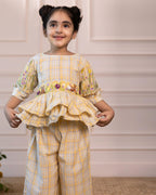 Adorable girls' yellow checkered co-ord set by Laad India, featuring intricate floral and animal embroidery, ruffled peplum top, and comfortable wide-leg pants. A perfect blend of vintage charm and modern elegance for your little one.