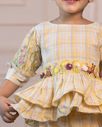 Adorable girls' yellow checkered co-ord set by Laad India, featuring intricate floral and animal embroidery, ruffled peplum top, and comfortable wide-leg pants. A perfect blend of vintage charm and modern elegance for your little one."