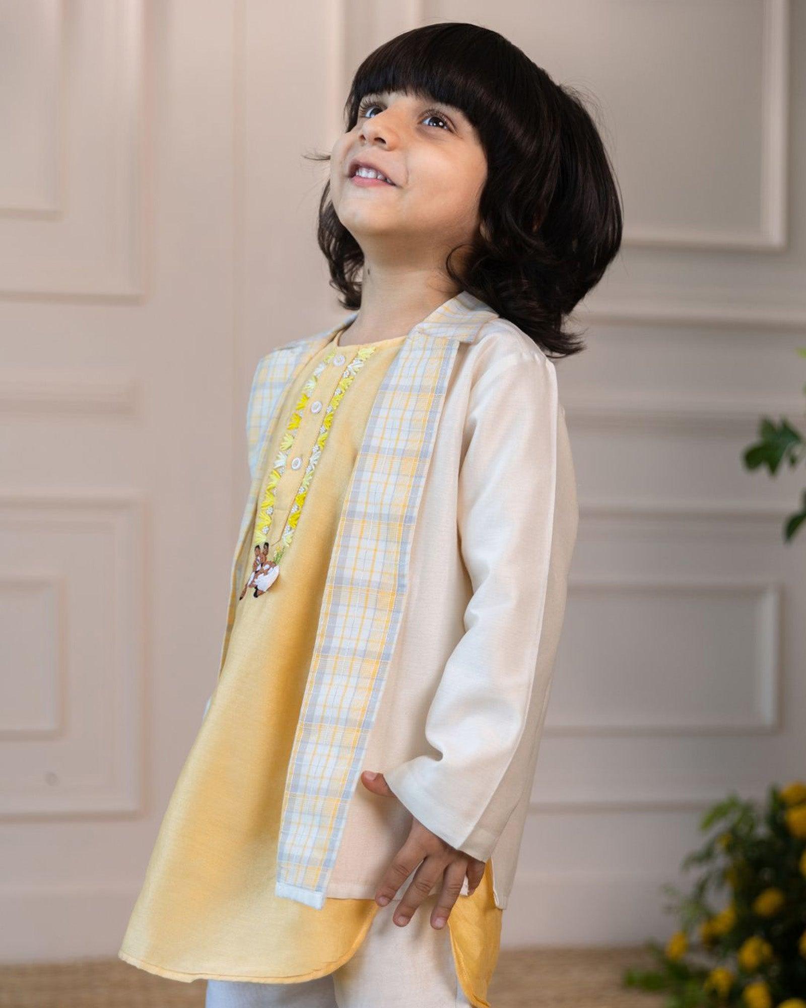 Laad`s kid wearing a pastel yellow kurta with embroidered reindeer details, paired with a checkered Nehru jacket and white trousers,
