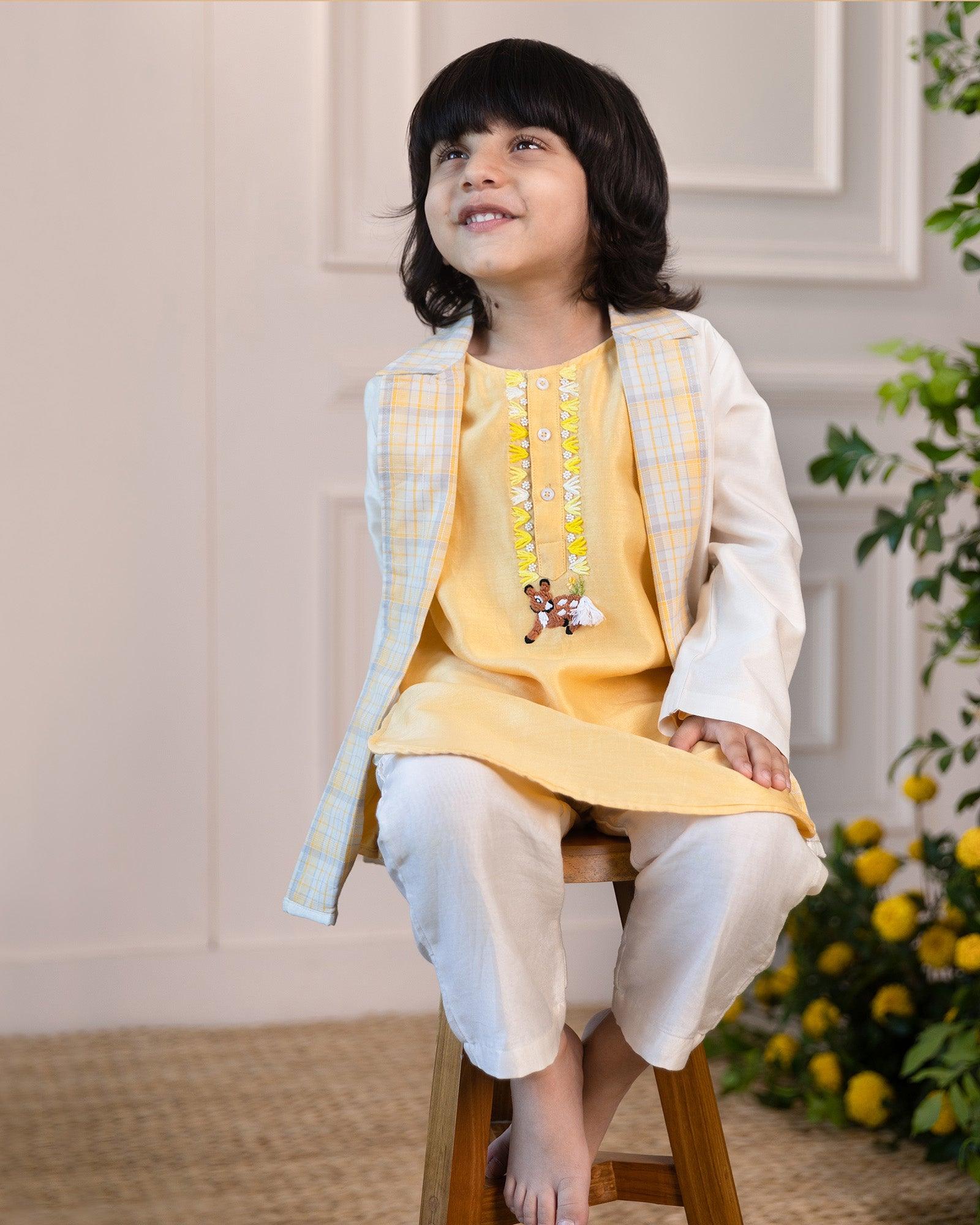 laad`s kid wearing  a pastel yellow kurta with embroidered reindeer details, paired with a checkered Nehru jacket and white trousers