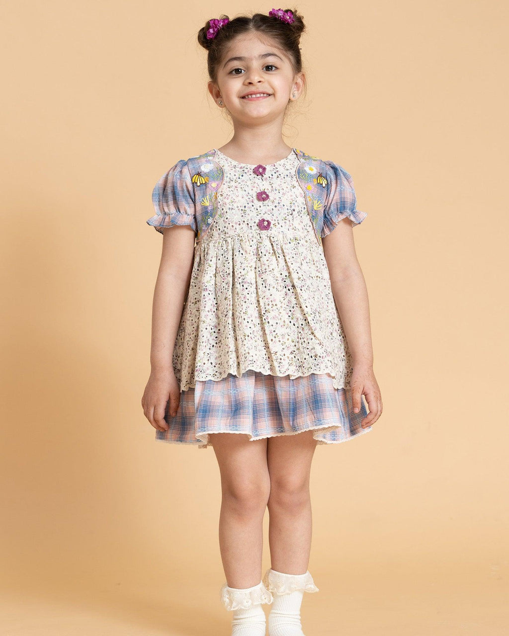 Laad`s kid in tea dress by Laad India, featuring delicate floral embroidery, plaid puff sleeves, and a charming layered design. Made with soft, breathable fabric, perfect for festive occasions and everyday elegance.