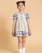 Laad`s kid in tea dress by Laad India, featuring delicate floral embroidery, plaid puff sleeves, and a charming layered design. Made with soft, breathable fabric, perfect for festive occasions and everyday elegance.