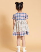 laad`s kid in tea dress by Laad India, featuring delicate floral embroidery, plaid puff sleeves, and a charming layered design. Made with soft, breathable fabric, perfect for festive occasions and everyday elegance."