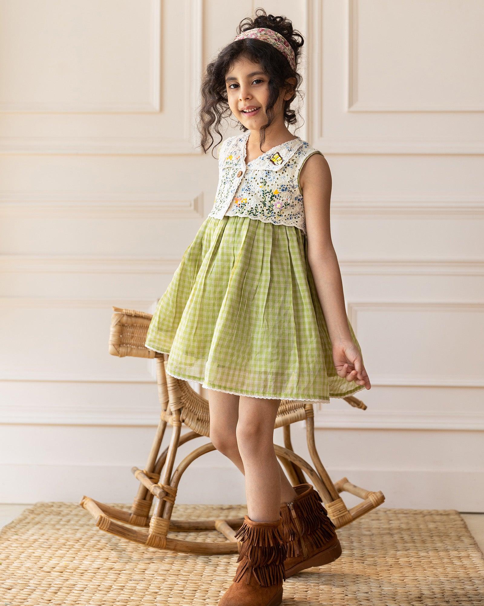 LAAD`S kid in Titalee moss green dress by Laad India, featuring delicate floral embroidery, an eyelet lace bodice, and a gingham checkered dress. A perfect blend of vintage elegance and modern comfort for your little one
