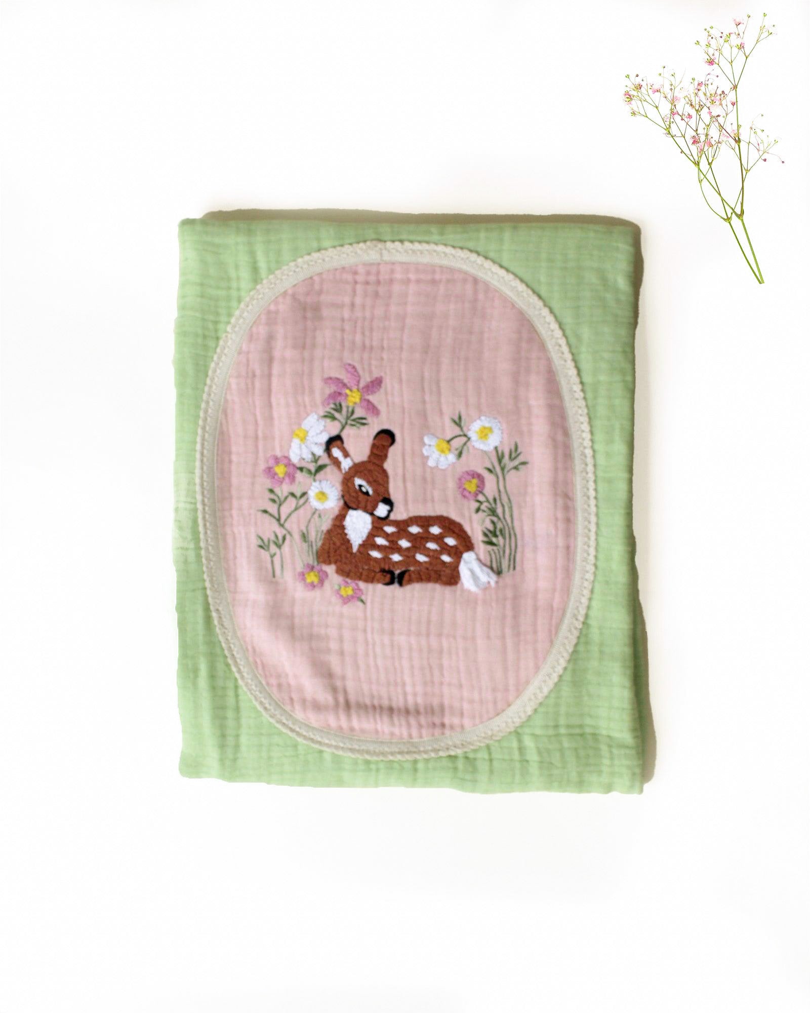 soft green muslin baby dohar featuring hand-embroidered floral details and a bambi nested on a pastel pink patch. Lightweight and breathable, ideal for keeping babies snug and cozy.