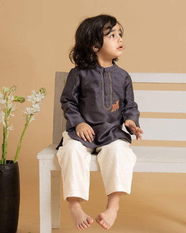Young boy wearing LAAD India vintage grape kurta with embroidered detail, paired with cream pants and a checkered sleeveless jacket, styled in festive kidswea
