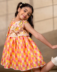 laad girl wearing a sleeveless zinnia dress set with with pink and yellow checkered print  and embroidered jacket 