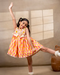 laad girl wearing a sleeveless zinnia dress set with with pink and yellow checkered print  and embroidered jacket 