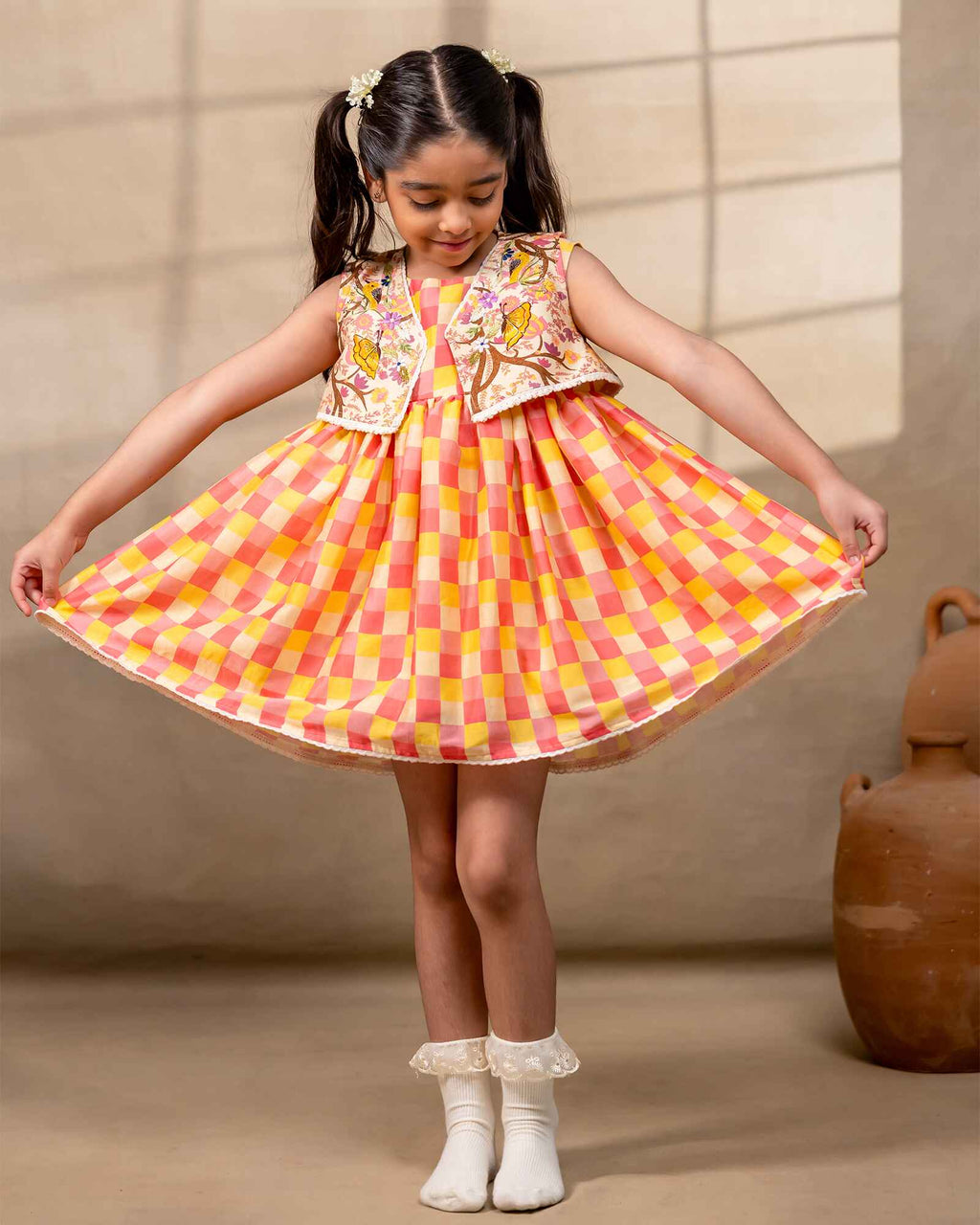 Girl wearing the Zinnia party wear DRESS featuring a vibrant checkered kurta with embroidered and printed jacket detailing , perfect for festive occasions and birthday party