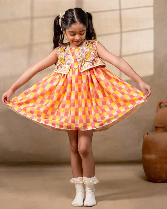 laad girl wearing a sleeveless zinnia dress set with with pink and yellow checkered print  and embroidered jacket 