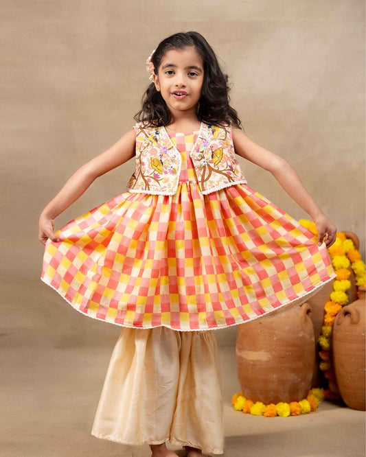 Girl wearing the Zinnia Sharara with jacket , featuring a vibrant checkered sharara party wear with embroidery  perfect for festive occasions , pooja , occasion wear and  weaddings 