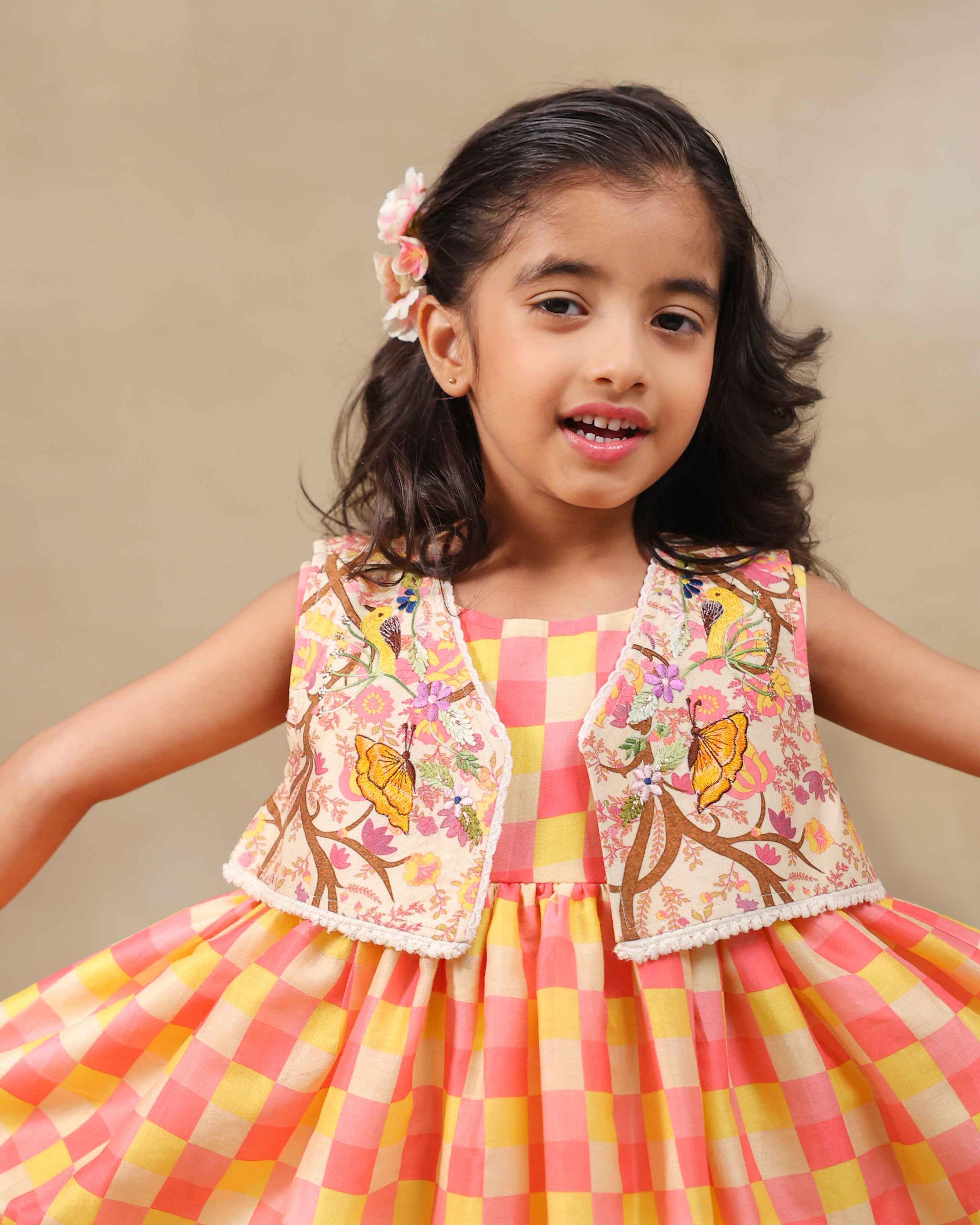 Girl wearing the Zinnia party wear DRESS featuring a vibrant checkered kurta with embroidered and printed jacket detailing , perfect for festive occasions and birthday party