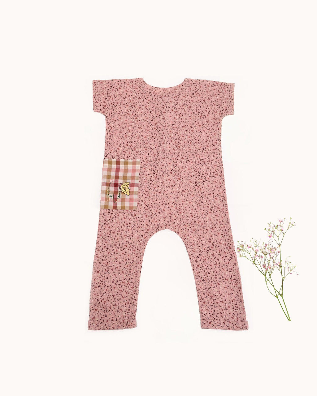 Laad`s child is wearing the adorable daisy onesie boasts a comfy round neck & wooden button front. A spacious pocket is adorned with charming hand-embroidered flowers & butterflies. Super soft fabric & a relaxed fit keep your little one happy & comfy all trip long!