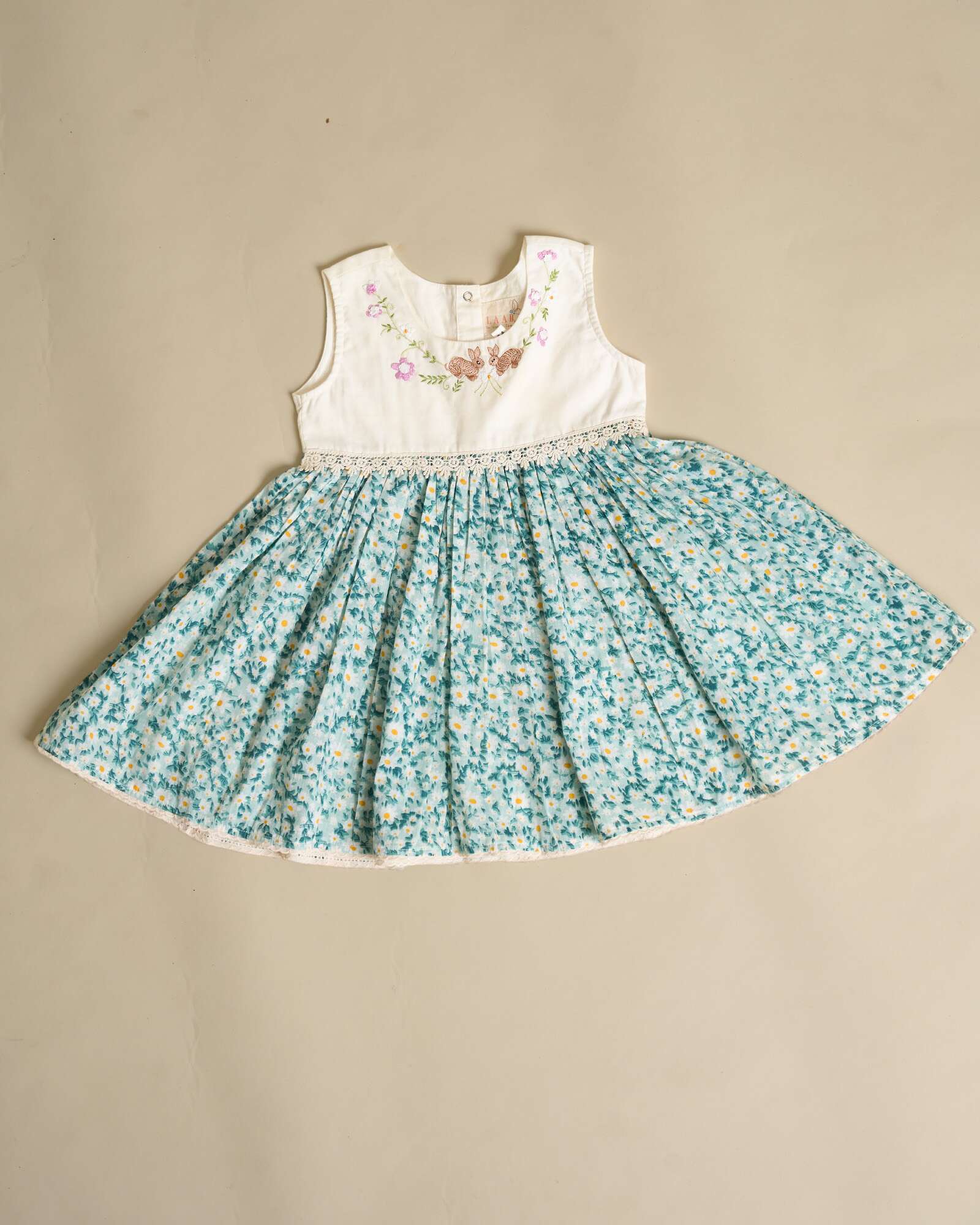 Flora dress has embroidered bunnies hop on the hand-stitched neckline. Cotton lace yoke adds charm. Breezy & comfy for warm days. Easy click-button back. SummerStyle 