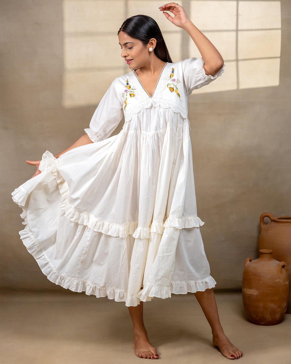 Woman wearing laad`s  white cotton midi dress with floral embroidery, scalloped neckline, and ruffled hem
