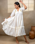 Woman wearing laad`s  white cotton midi dress with floral embroidery, scalloped neckline, and ruffled hem