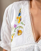 Woman wearing laad`s  white cotton midi dress with floral embroidery, scalloped neckline, and ruffled hem