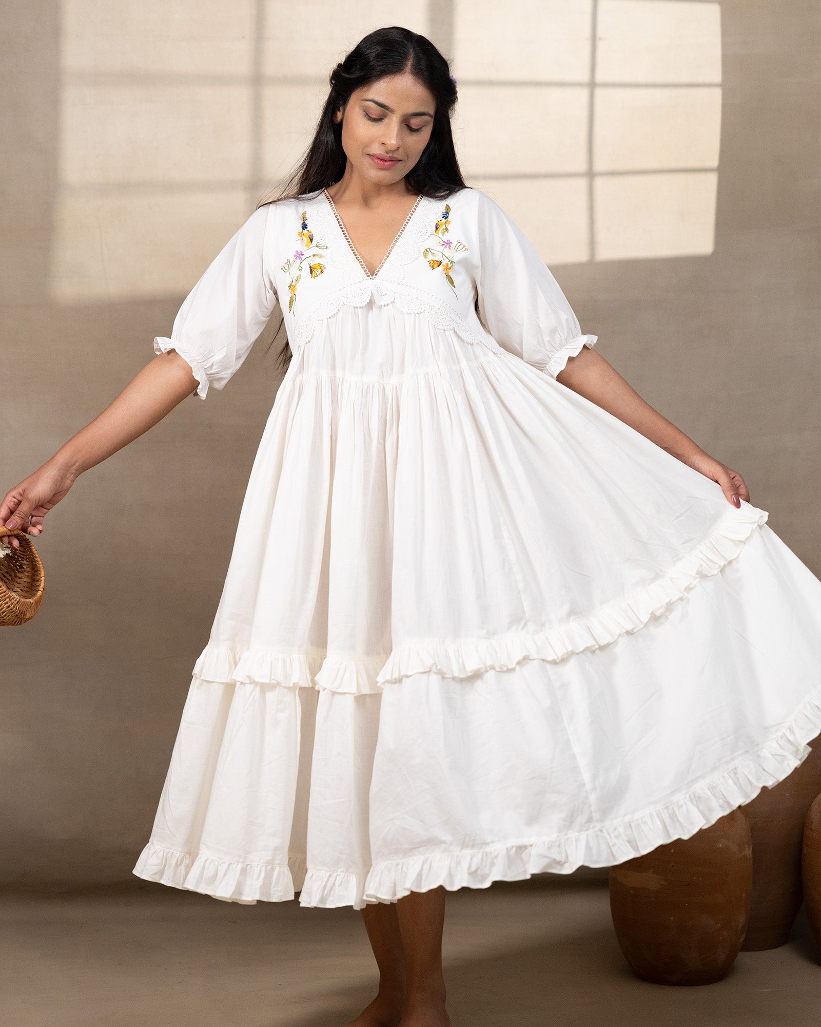 Woman wearing laad`s  white cotton midi dress with floral embroidery, scalloped neckline, and ruffled hem