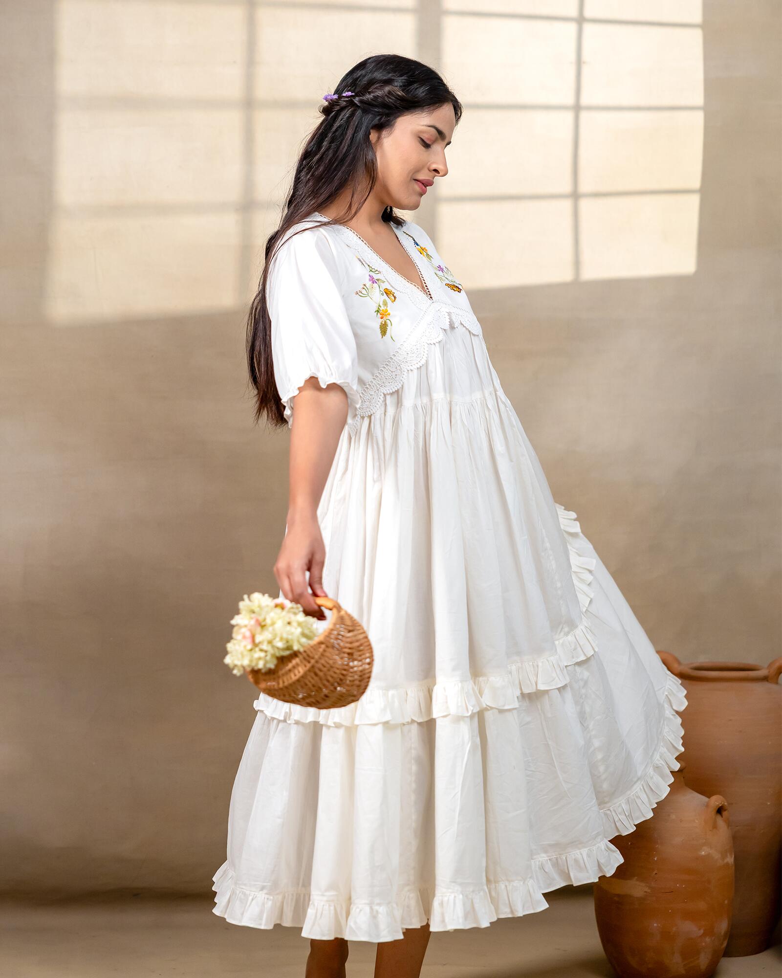 Woman wearing laad`s  white cotton midi dress with floral embroidery, scalloped neckline, and ruffled hem