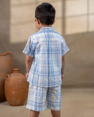 LAAD`S kids in co-ord set featuring a light blue and white plaid short-sleeve button-up shirt with matching shorts. The shirt is adorned with delicate embroidery of a rocking horse on the chest,