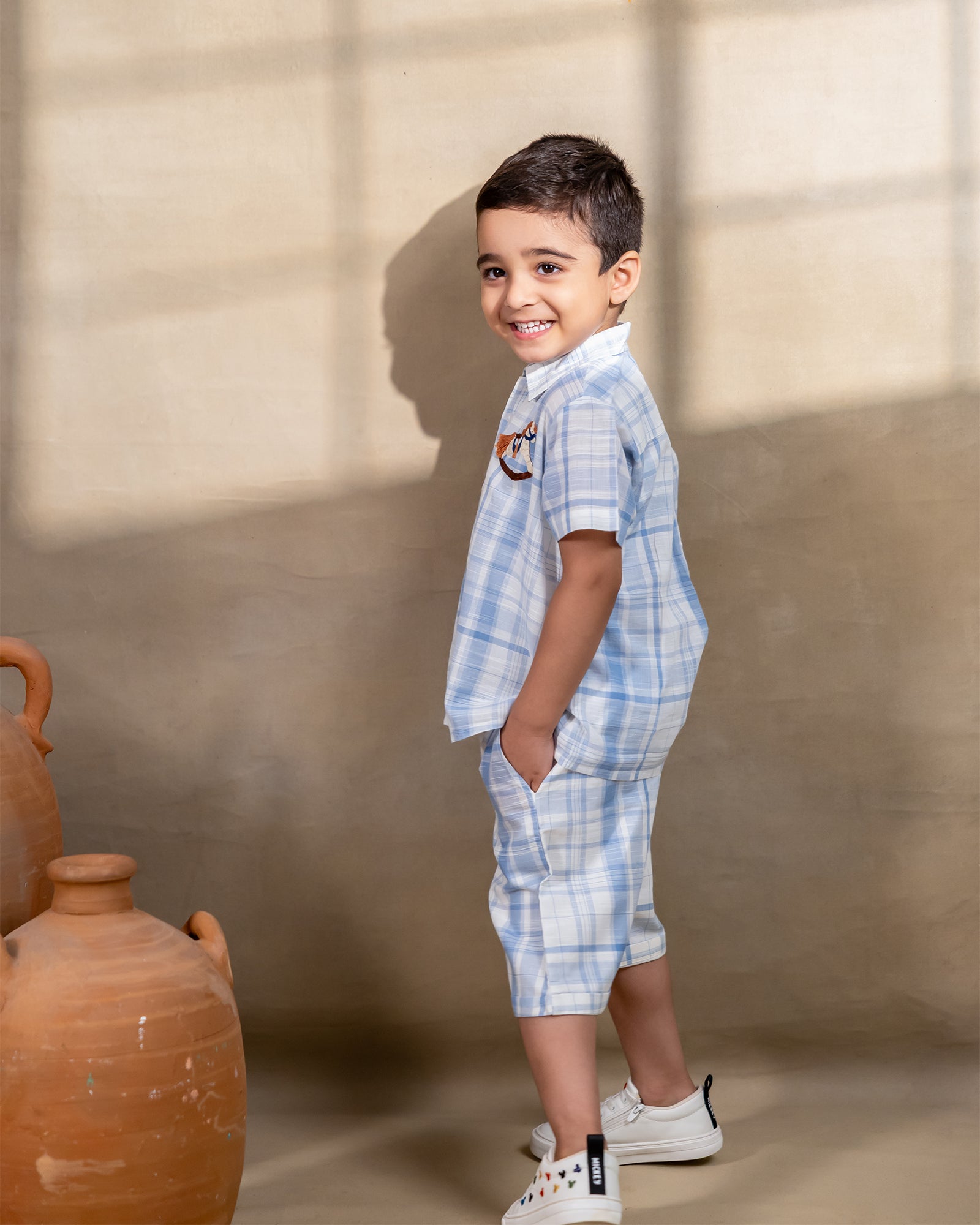 LAAD`S kids in co-ord set featuring a light blue and white plaid short-sleeve button-up shirt with matching shorts. The shirt is adorned with delicate embroidery of a rocking horse on the chest,