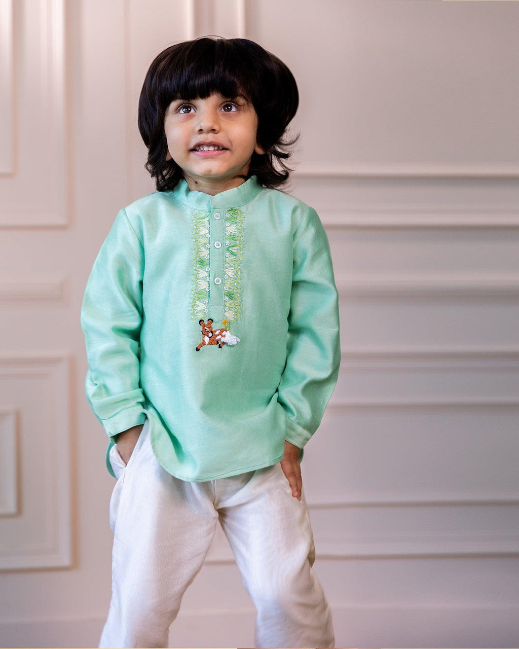 laad`s kid in short kurta featuring a bandhgala collar, hand-embroidered featuring bambi. Paired with ivory pants.