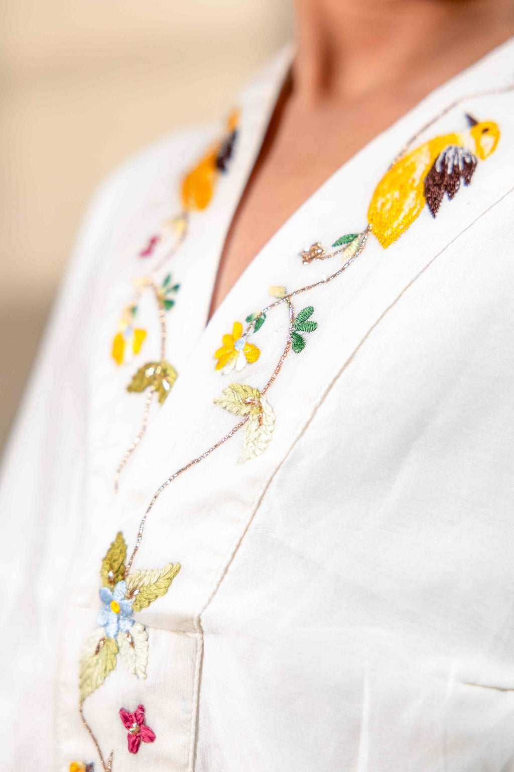 Little girl in a white hand-embroidered A-line girls party dress with flared sleeves and colorful bird and floral detailing, holding a wicker basket.