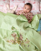 Soft green baby dohar with delicate embroidery featuring two bunnies surrounded by a floral wreath. Made from lightweight, breathable fabric with a satin border—perfect for cozy naps and gentle on baby’s skin.