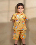 A cheerful boy`s Laad`s co-ord set boy`s shirt and shorts in a vibrant yellow hue, featuring playful deer and geometric prints, a collared button-down shirt, and matching shorts.