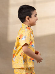 A cheerful Laad`s co-ord set in a vibrant yellow hue, featuring playful deer and geometric prints, a collared button-down shirt, and matching shorts.