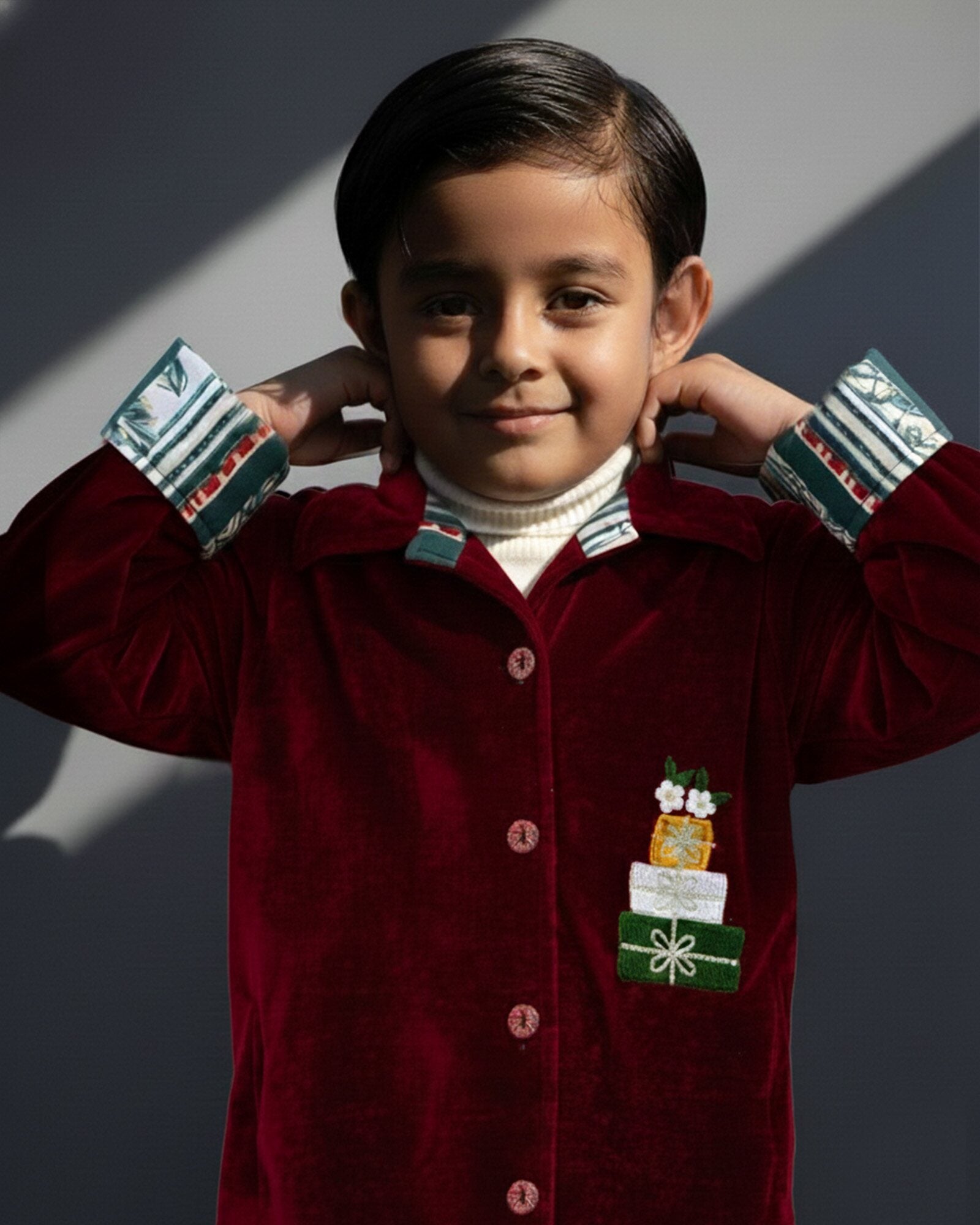 redvelvet co-ord set by LAADINDIA.com, featuring a child dressed in a red velvet co-ord with  embroidery, front-open top with contrast check cuffs, and matching trousers for winter occasion wear.