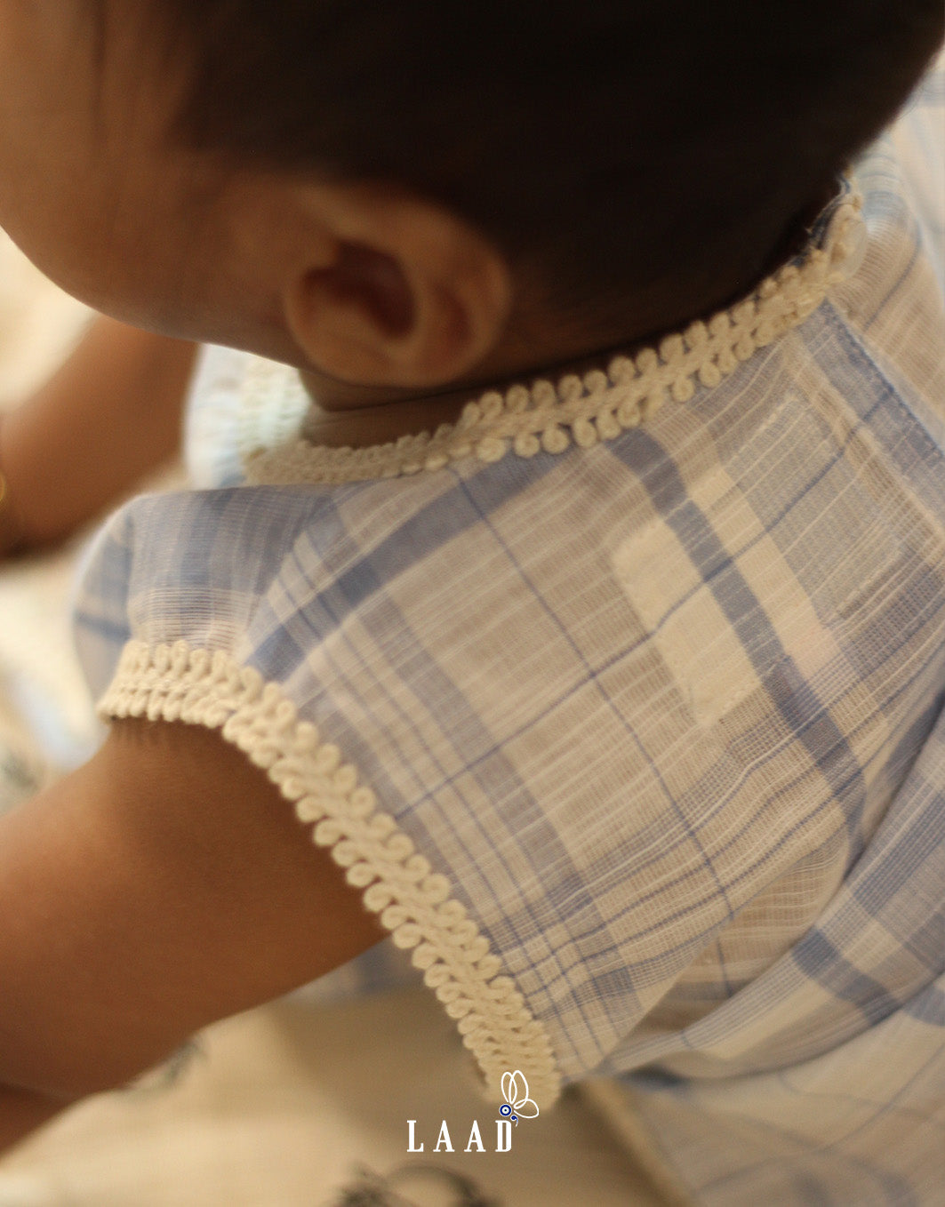 baby in LAAD`S  soft blue plaid jhabla featuring delicate lace trim and a floral pocket, paired with diaper cover