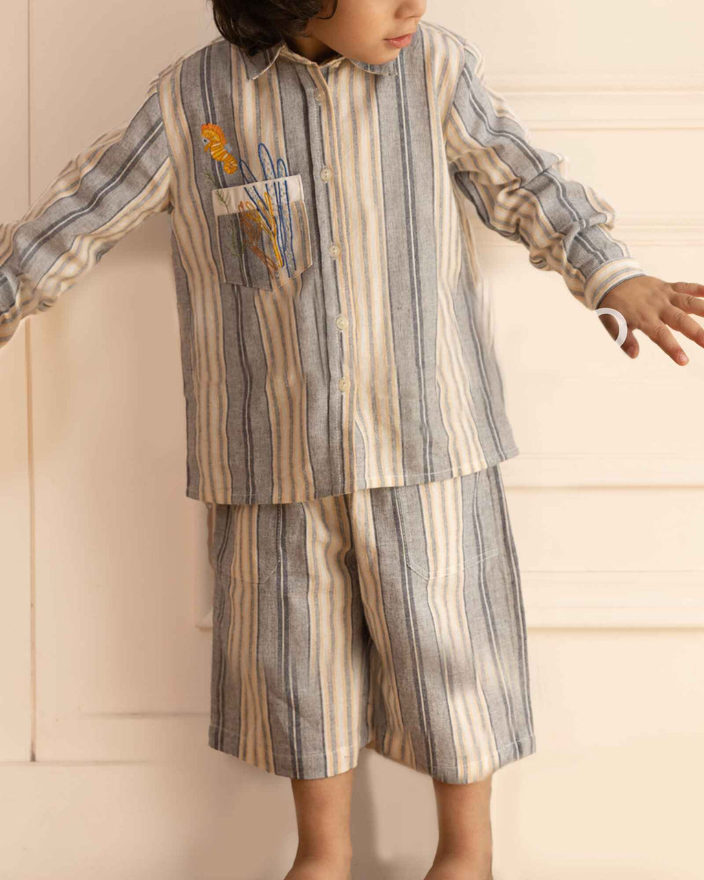 laad`s Kids' striped co-ord set with a long-sleeve shirt and shorts, featuring soft beige and gray tones. Embroidered seahorse detail adds a playful touch. Lightweight, breathable fabric for all-day comfort.
